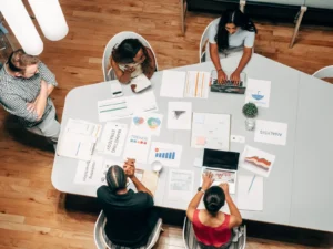 Agência de Marketing Digital em Curitiba - Lab Growth 77 Equipe de agência analisando peças de uma campanha numa mesa de reunião