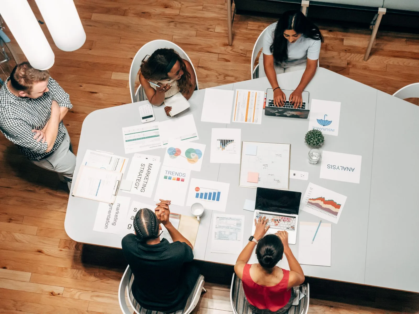 Equipe de agência analisando peças de uma campanha numa mesa de reunião