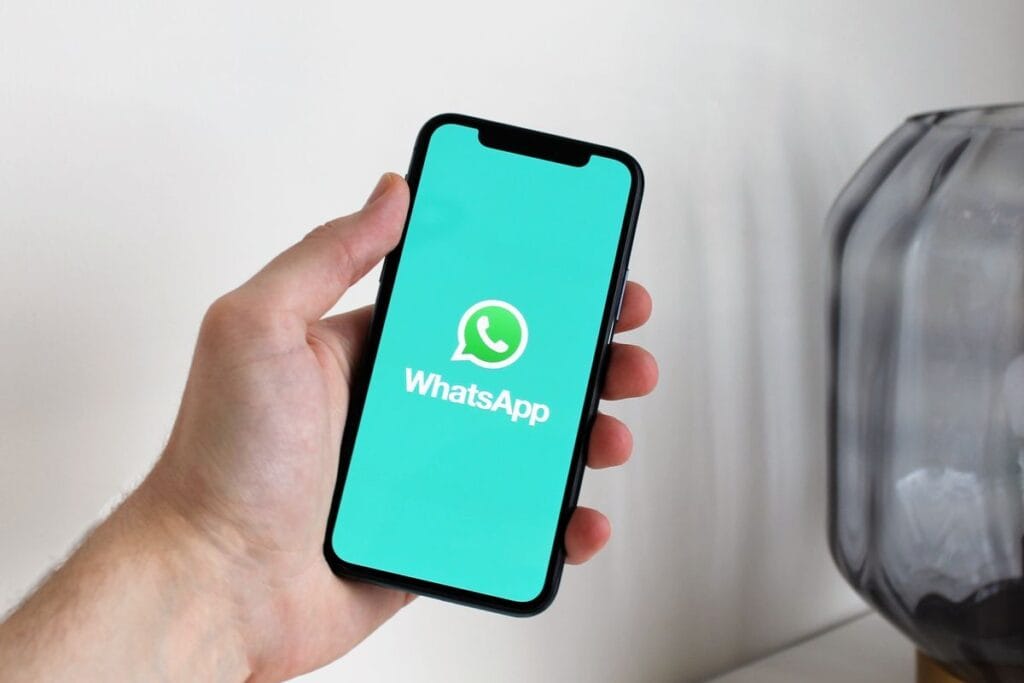 Automação no WhatsApp: o que pode (e o que não pode) ser automatizado 3 Mão segurando um celular com o aplicativo WhatsApp aberto