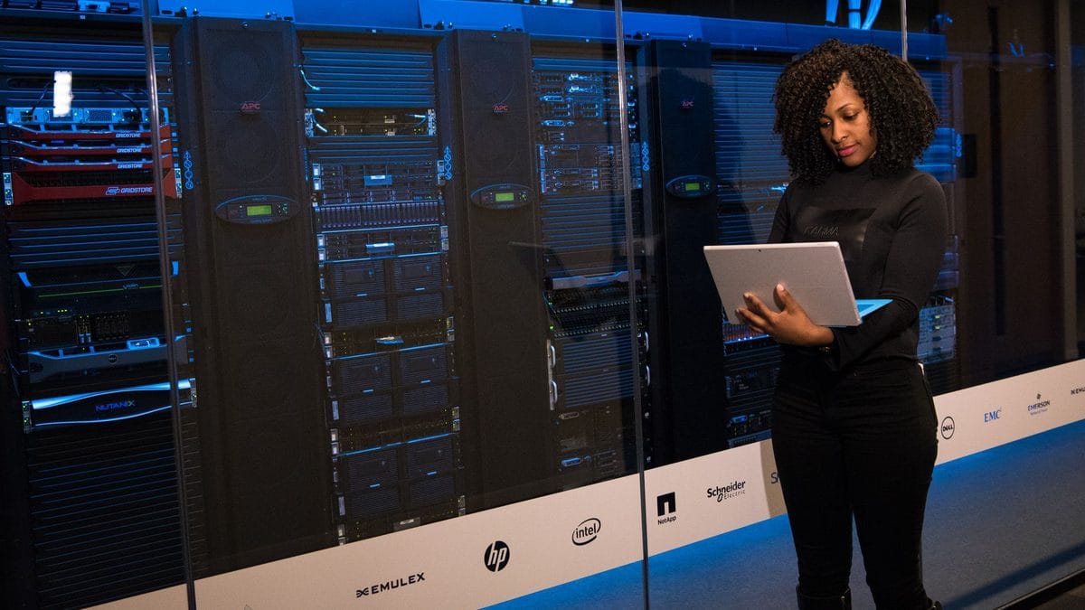 Profissional com notebook ao lado dos servidores de um data center